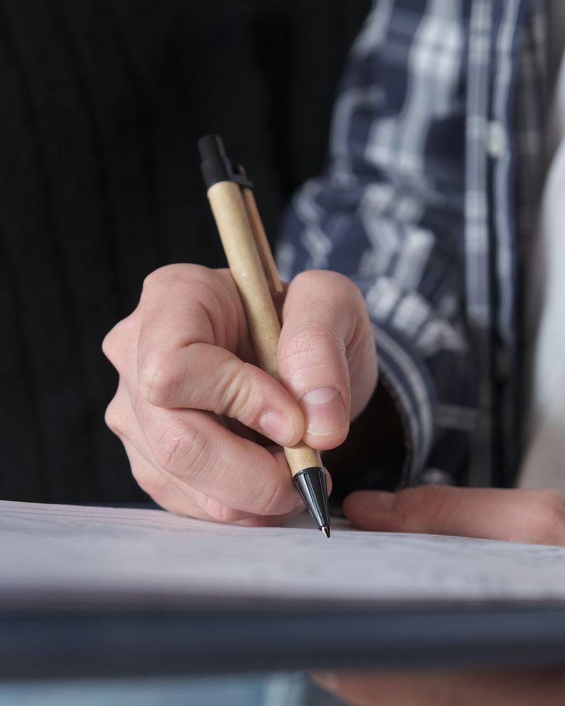 Mano firmando un documento con un lápiz
