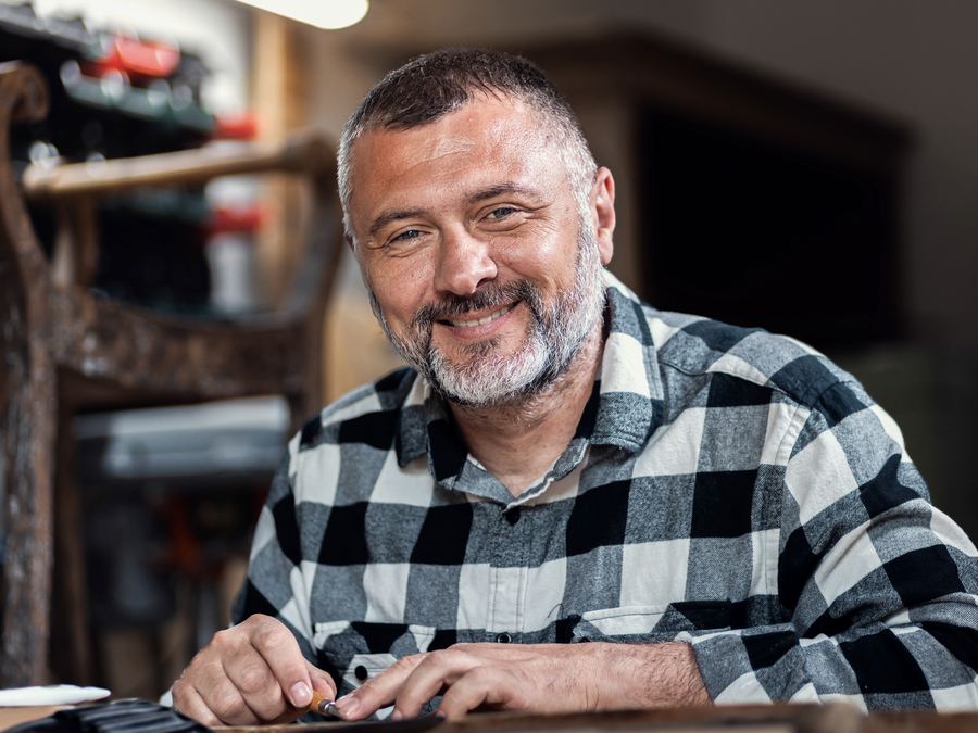 Artesano sonriendo mientras trabaja en su taller